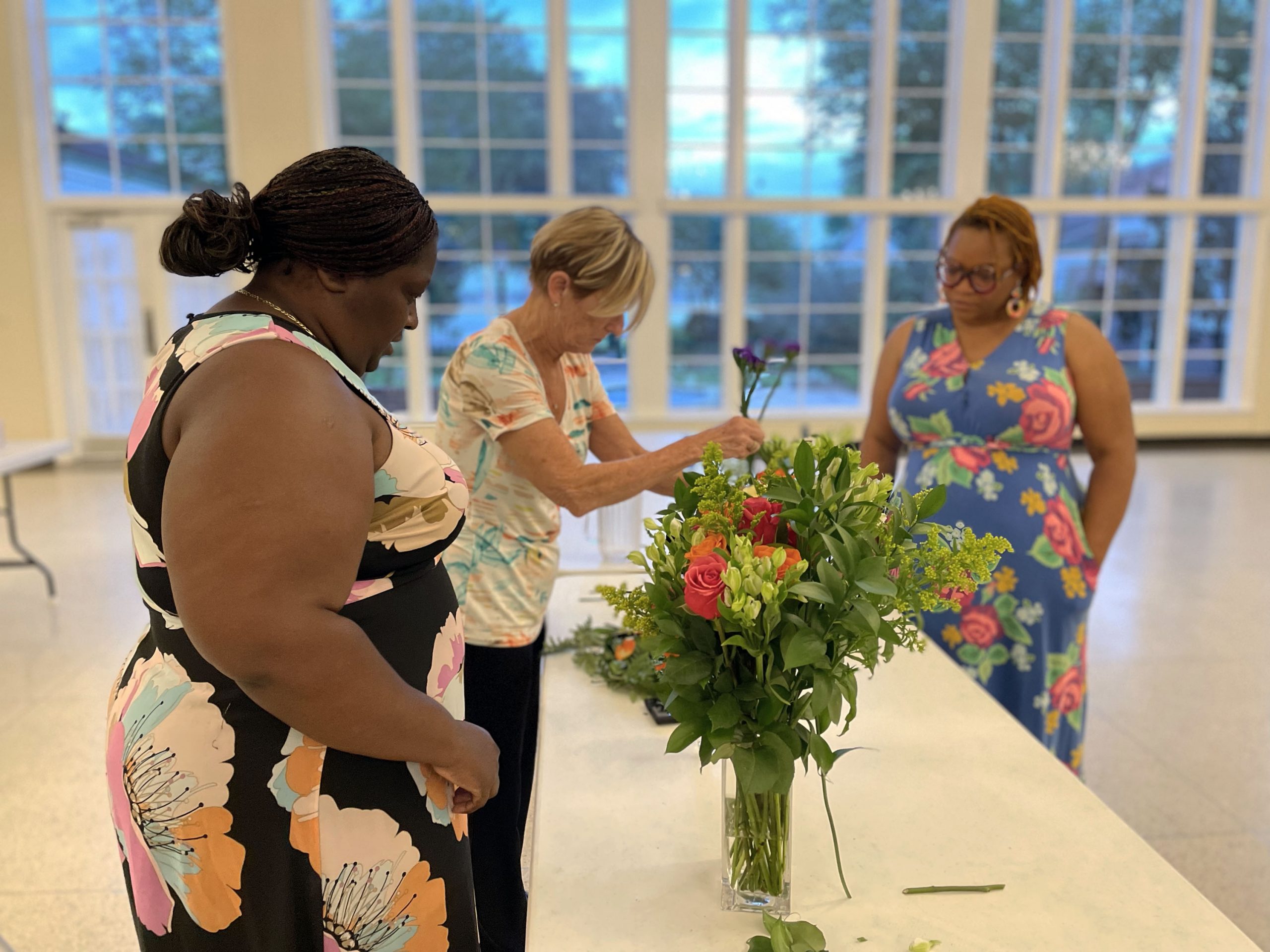 Two guests and the instructor create flower arrangements